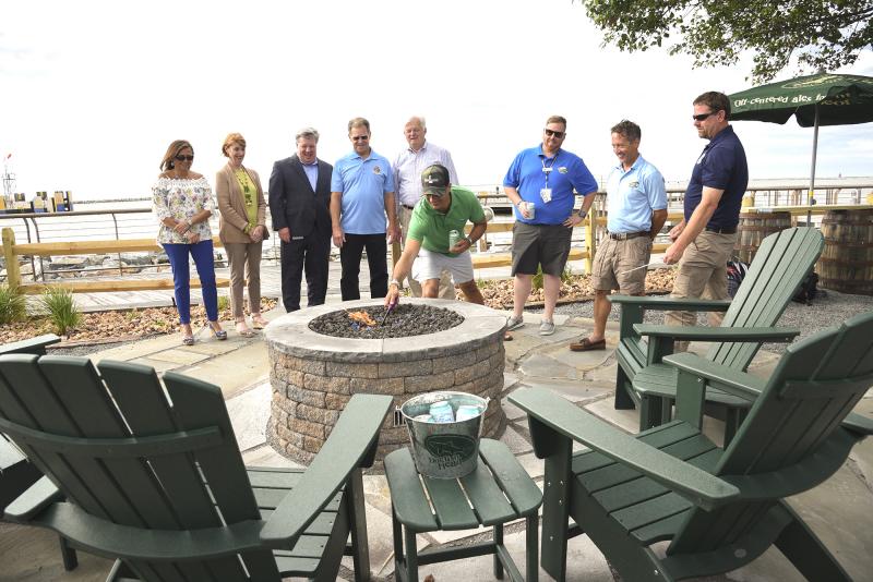 In off-centered fashion, the ribbon-cutting ceremony was a ceremonial fire pit lighting. Shown are (l-r) Nikky Fisher, rising board president, Lewes Chamber of Commerce; President of Lewes Chamber of Commerce Betsy Reamer; Tom Cook, executive director DRBA; Jim Ford, DRBA commissioner; Lewes Mayor Ted Becker; Sam Calagione, founder of Dogfish Head Craft Brewery; Shaun O’Brien, superintendent of food and retail for the ferry; Heath Gehrke, director of Cape May-Lewes Ferry operations; Charles Short, director of maintenance. DENY HOWETH PHOTOS